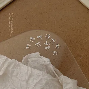 Macro shot of 20 silver mini alloy bow charms for nail art and DIY jewelry crafts