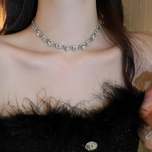 Close-up of sparkling heart-shaped zircon choker necklace on model in elegant black dress