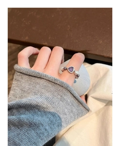 Detail of a pearl stretch ring with a purple heart-shaped zircon stone on a hand