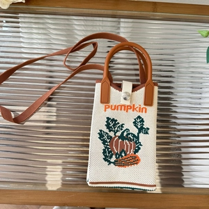 Detailed knit texture of a mini pumpkin crossbody bag with leather handles on glass