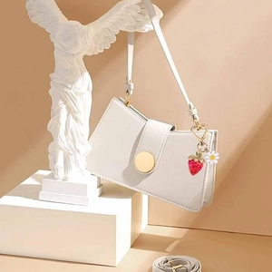 White shoulder bag with strawberry and daisy charm on a white classical bust