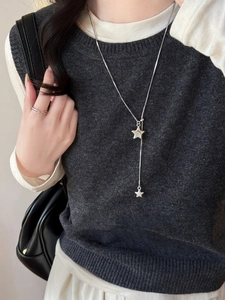 Close-up of silver asymmetric star pendant necklace and ring on a grey knit sweater