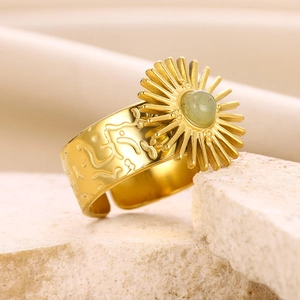 Detailed view of a gold sunflower ring with turquoise gemstone on a beige stone surface
