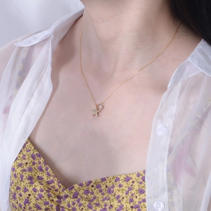 Close-up of a gold starfish necklace with crystals and a pearl worn by a model