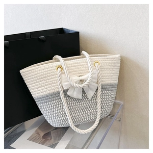 Detail of woven tote bag with white bow accent and chunky rope handles on display