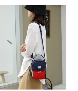 Detailed view of navy blue and red nylon crossbody bag with multi-layer zipper pockets
