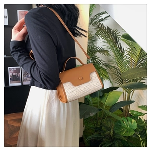Détail du sac à bandoulière minimaliste en paille et similicuir marron porté par un mannequin
