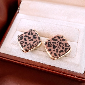 Detailed close-up of square leopard print stud earrings with golden metal borders
