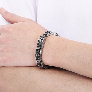 Macro shot of vintage titanium steel bracelet showing detailed wolf head and floral carvings