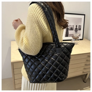 Détail du sac cabas matelassé noir avec motif losanges et fini brillant sur le modèle
