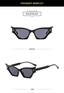 Detail view of black cat-eye Y2K sunglasses with distinctive gold metal hardware accents