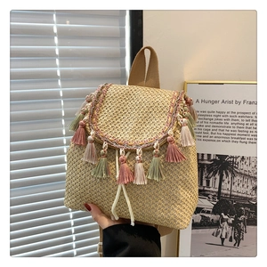 Detail of a straw bucket bag with colorful tassels and drawstring closure in a sunny scene