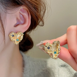 Detailed macro view of heart-shaped gold studs with lava texture and colored rhinestones