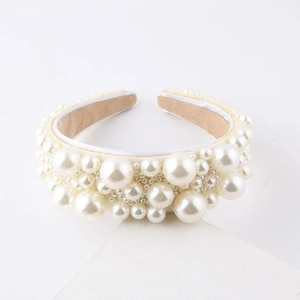 Elegant wide headband with clustered faux pearls on a minimalist white background