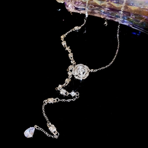 Detail of silver rose pendant with crystal drops and water drop tassel on black background