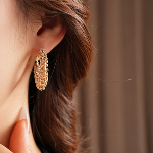 Close-up of elegant gold C-shaped hoop earrings with sparkling rhinestones on a model
