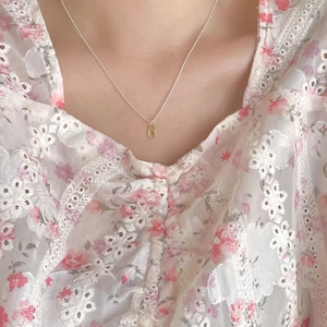 Close-up of minimalist gold oval pendant on a fine bead chain necklace worn by a model