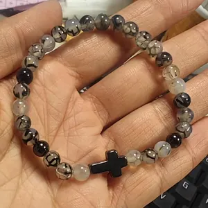 Gros plan d'un bracelet en perles de pierre naturelle 6mm avec pendentif croix noire