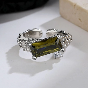 Macro shot of textured silver ring featuring rectangular green and white cubic zirconia