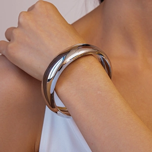 Detailed close-up of a silver polished metallic cuff bracelet with organic fluid design
