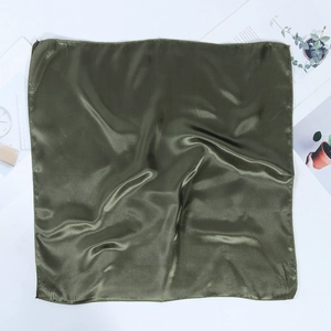 Detailed close-up of dark green silk square scarf fabric showing smooth glossy texture