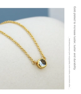 Macro shot of 18K gold plated necklace with round light blue zircon pendant on stone