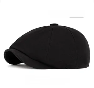 Detail view of a black octagonal newsboy cap with top button and twill cotton stitching