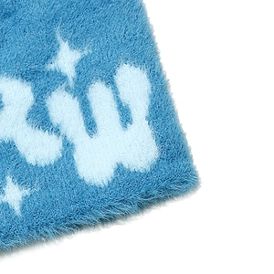 Macro detail of blue plush knit beanie with star pattern and letter W embroidery
