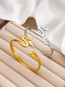 Detailed close-up of gold and silver snake-shaped cuff bracelets on beige velvet