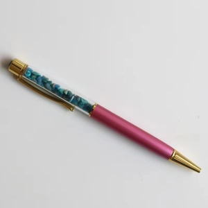 Detail of creative ballpoint pen featuring turquoise crystal stones and gold accents