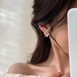 Elegant butterfly earrings with pearlescent finish on model with soft lighting