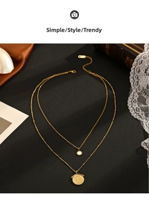 Detail of 14K gold double-layer necklace with sunburst and coin pendants on black velvet