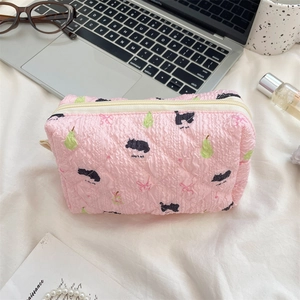 Rosa gesteppte Kosmetiktasche mit süßen Katzenmotiven auf einem Schreibtisch mit Deko