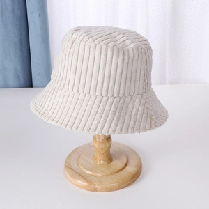 Detailed close-up of a beige corduroy bucket hat displayed on a wooden stand