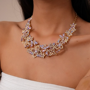 Detail of luxury gold flower necklace with purple crystals and rhinestones on a model