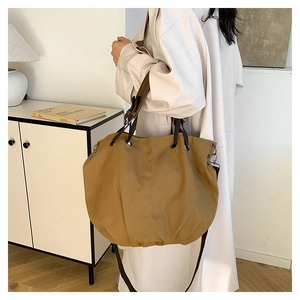 Detail of khaki canvas tote with dark brown strap and vintage metal eyelet accents