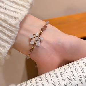 Detail of star-shaped crystal charm and strawberry quartz on woven beaded bracelet