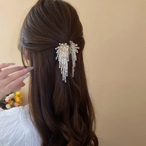 Macro detail of artificial pearl fringe hair claw clip with elegant cascading tassel design