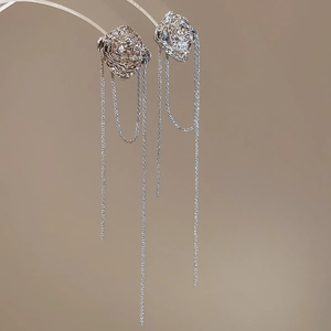 Detailed close-up of irregular silver earrings featuring long flowing metal tassels