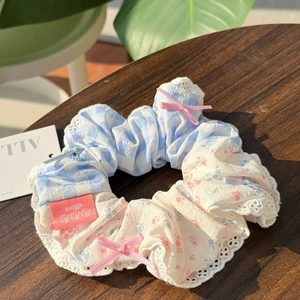 Detail of blue plaid and floral hair scrunchie with lace trim and pink ribbon bows