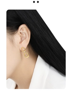Close-up of minimalist geometric double oval hoop earrings in polished gold on a model