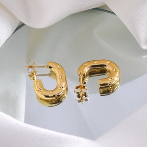 Detailed view of gold horseshoe earrings with star engravings on a silk reflective surface