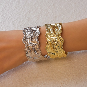 Detailed macro view of gold and silver lava texture metal bracelets with rippled surface