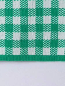 Detail of green and white checkered knit fabric with ribbed edges and fine texture