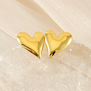 Close-up of golden 18K gold-plated heart-shaped stud earrings on ice crystal stand