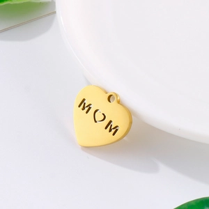 Golden stainless steel heart pendant with hollow MOM design on a white plate