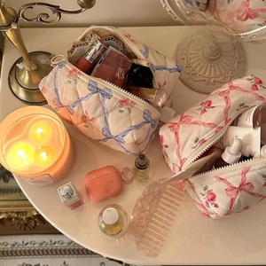 Quilted floral cosmetic bags with ribbon bows displayed on a warm vintage vanity table