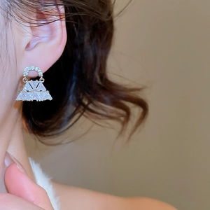 Primo piano di un orecchino a borsa triangolare in argento con zirconi indossato sull'orecchio