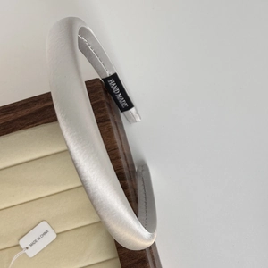 Detail of a pearl white satin headband displayed on a vintage wood jewelry box