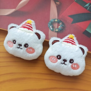Detail of two white plush cat pins with festive Christmas hats on wooden surface
